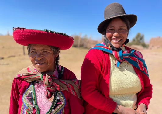 Two locals in colorful garb, both looking at camera, smiling.