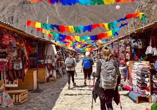 Guests walking through marketplace, colorful banners an mountain range above them.