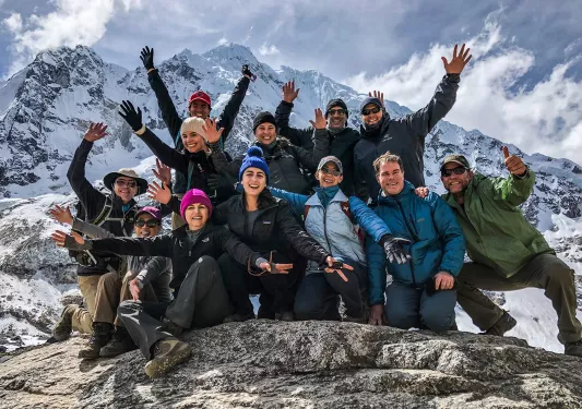 Group of guests on mountainside, all smiling, gesturing to camera.