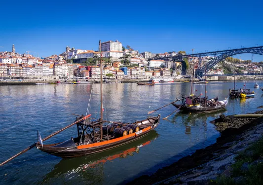 Shot of Porto river, boats, riverside houses, bridge in distance. 