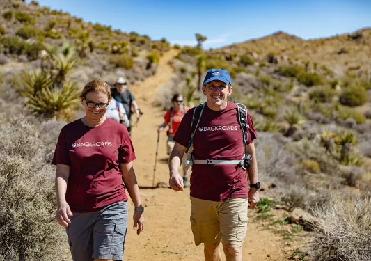 Guests on desert trail, one is smiling at camera.
