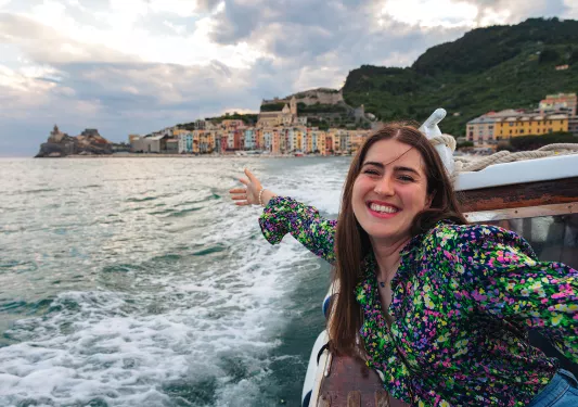 Young guest on boat, gesturing to coastal city.