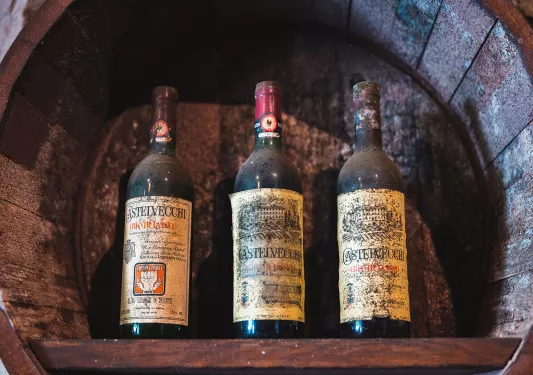 Three very old, dust covered bottles of red wine.