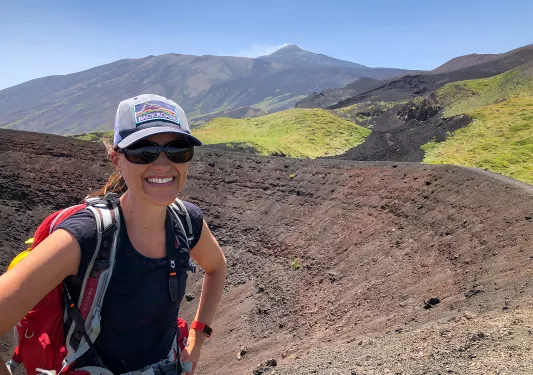 Guest taking selfie while standing in a small caldera. Mountains behind them.