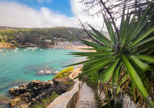 POV shot on stone stairs, blue ocean to left, beach town ahead.