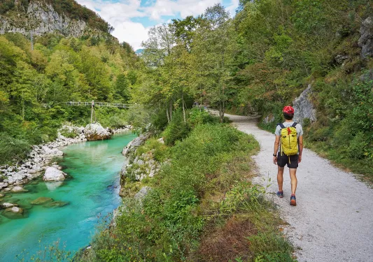 Hiker on trail alongside river.