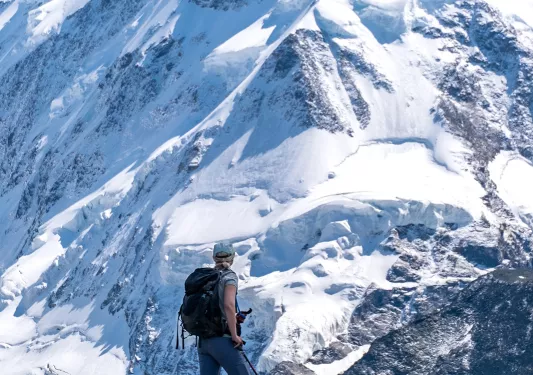 Hiker looking at expanse of snowy Alps  mountains.