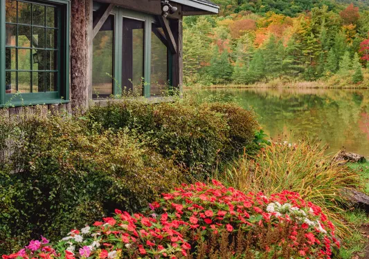 Shot of lakeside building, colorful bushes in foreground.