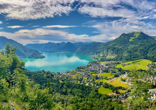 Lake surrounded by mountain range and towns in Europe.