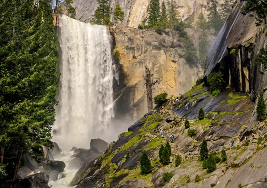 Shot of waterfall, craggy riverbed in foreground.
