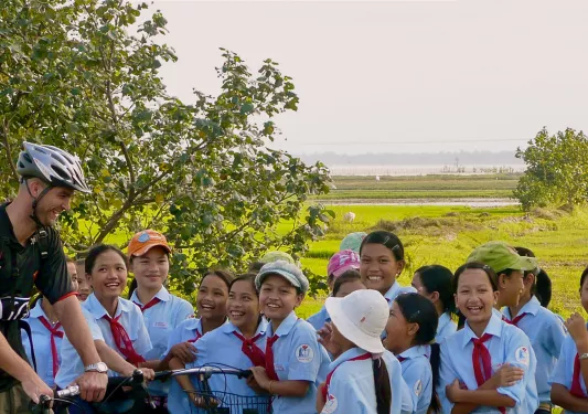 Backroads biker laughing with a group of children in Vietnam