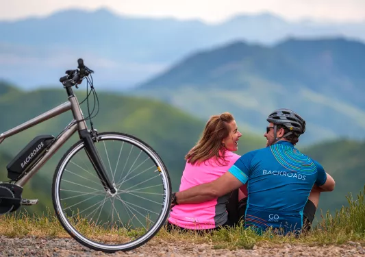 Cyclists sitting on a hill together in front of a Backroads ebike.