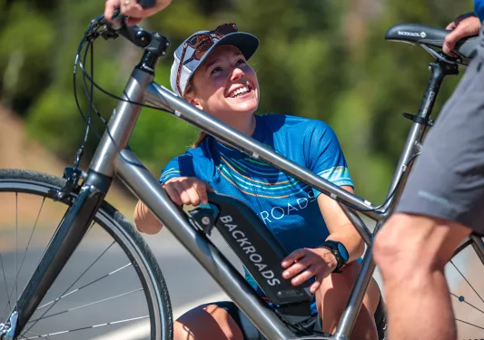 Backroads leader assisting cyclist with e-bike.