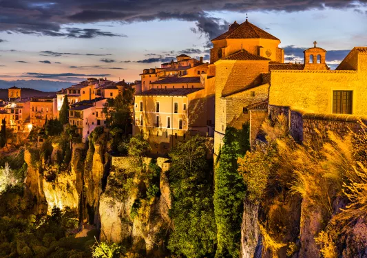 Sunset-lit cliffside, white houses above.