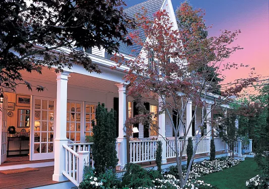 Exterior view of a white lodge with trees and the sunset in the background