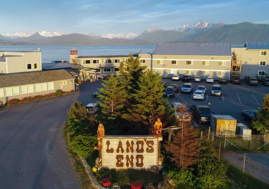 Exterior view of hotel buildings next to a large lake and tall mountains in the background
