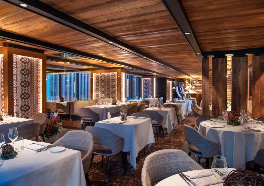 Indoor dining hall in a wooden lodge-style room, with gray cushioned chairs