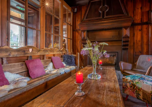 Indoor lodge with wooden furniture and leather seats, with a fireplace at the end of the room