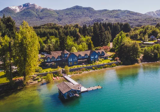 Sky view of blue lodge with a small pier and a large lake in the front