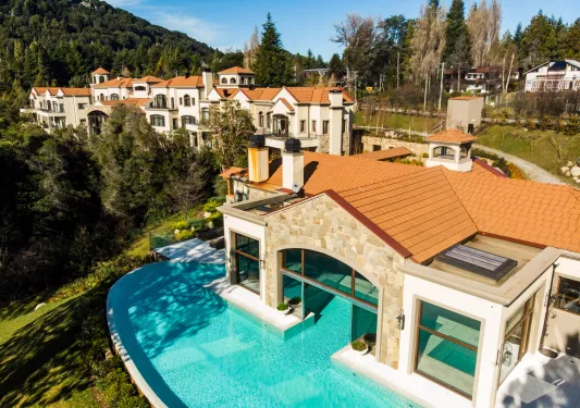 White and brown buildings with a pool surrounding one of the buildings