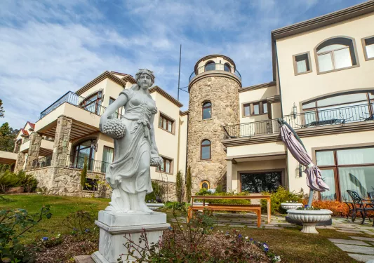 Exterior view of tan and stone building with a stone statue in the front