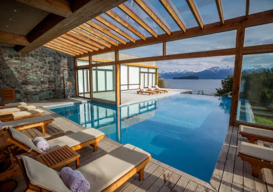 Outdoor pool with reclining chairs, looking out to snow-capped mountains in the distance