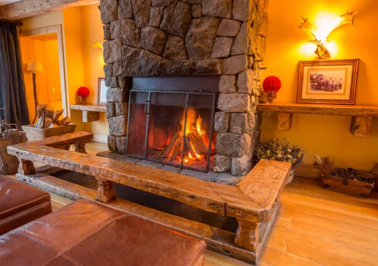 Stone fireplace with illuminated portraits on either side, with a wooden bench in front