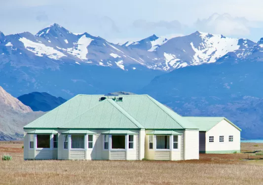 house with green roof in front of snow capped mountains
