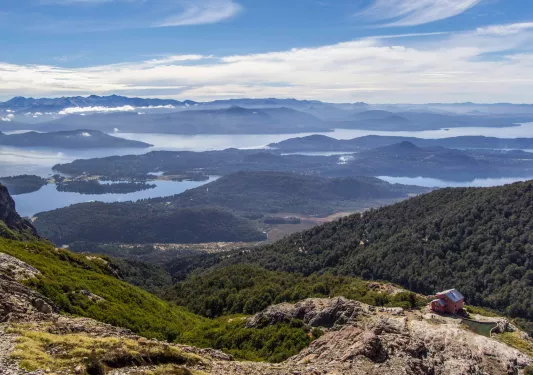 House on top of a mountain, with a valley of trees in the distance