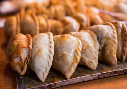 Empanadas lined up on a steel plate