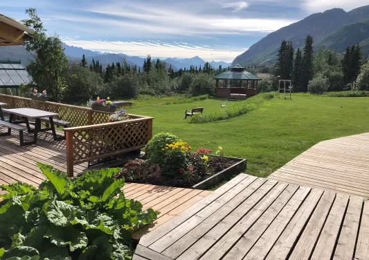 Outdoor patio with a wooden walkway and an open grass field looking out to the mountains