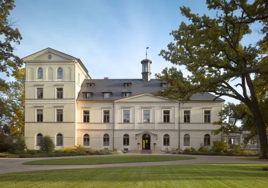 Exterior view of a yellow building, with a large grass area in front