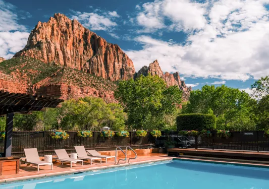 pool with lounge chairs and mountains in background