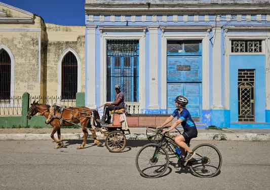 Woman riding a bike while looking at a man on a horse carriage