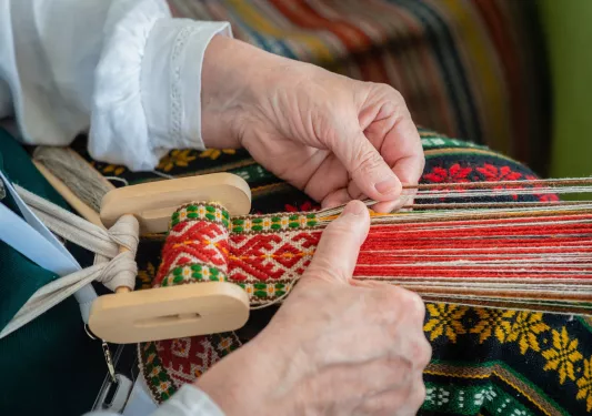 Hands weaving on a loom