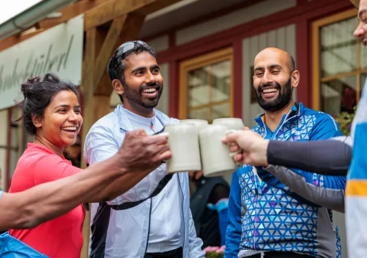 Group of people with beer steins clinking their mugs and laughing