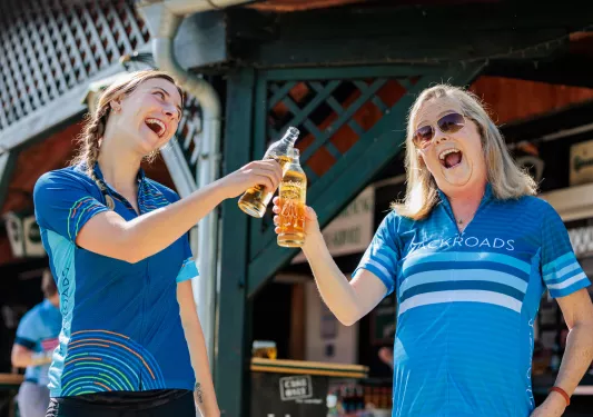 Two woman clinking their bottles of drinks and smiling