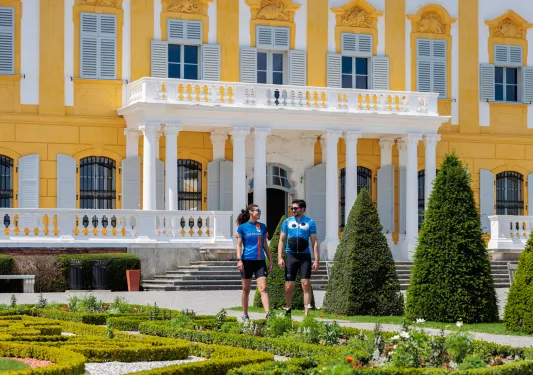 Man and woman in front of a yellow and white building at an outdoor garden
