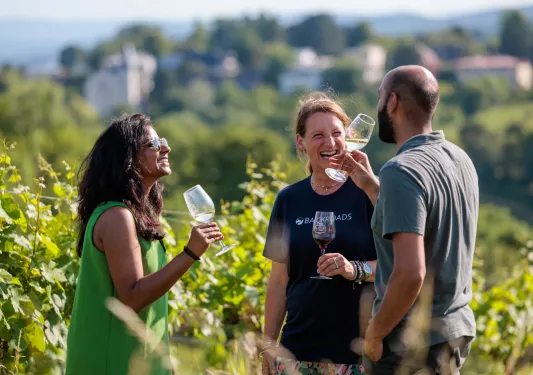 Two women and a man drinking glasses of wine and laughing
