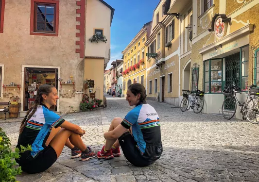 Two women sitting on the floor of a stone pathway 