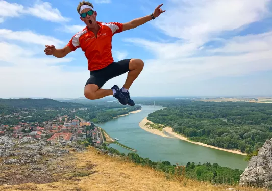 Man jumping up on a cliffside with a river in the distance