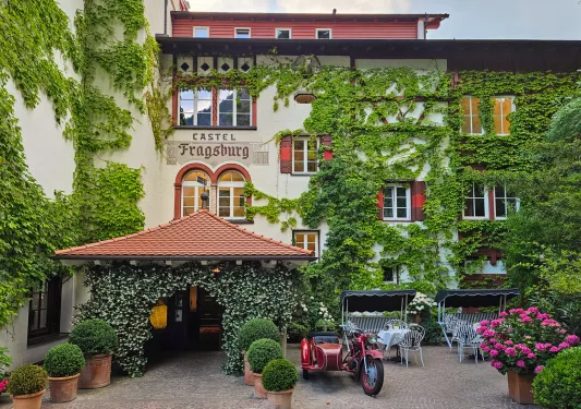ivy covered hotel entrance with bistro tables out front