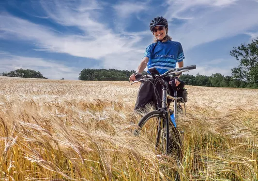 Woman in a field of wheat on her bike