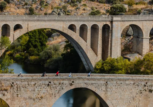 Group of people biking on a stone bridge