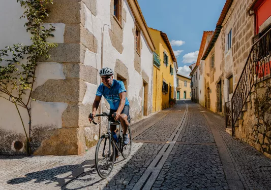 Man smiling while riding a bike in a stone alleyway