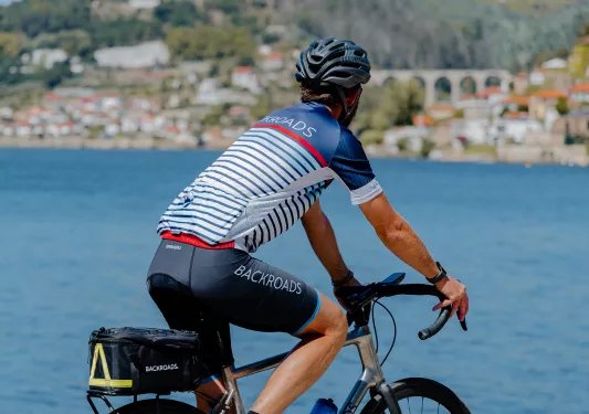 The back of a man biking while looking out to an ocean