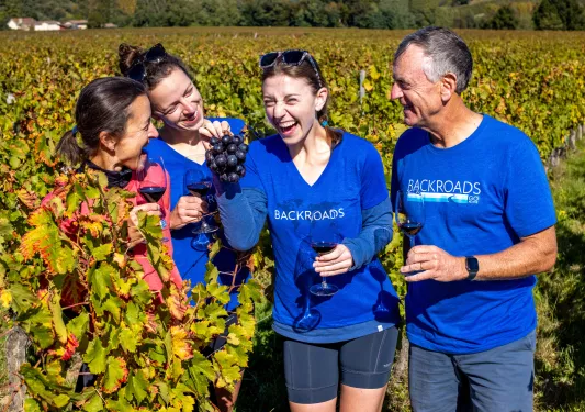 Group of people in a vineyard holding up bundles of grapes