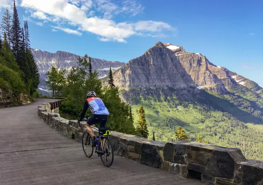 Man riding a bike on a windy road with a mountain in the distance