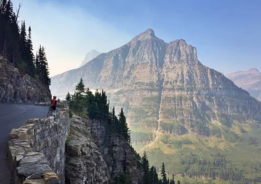 Solo biker looking over a wall into a mounatin valley