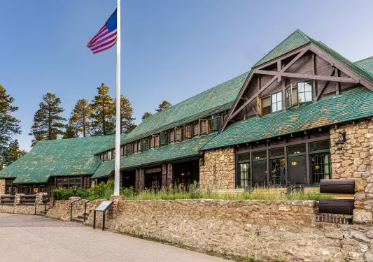 Stone building with green roofing and an American Flag on a pole